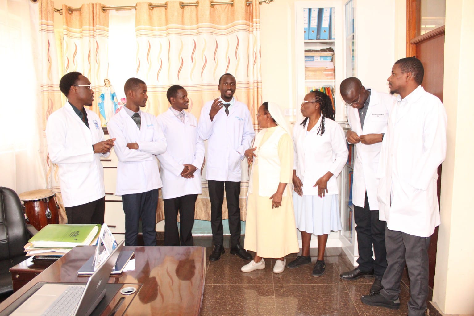 Tutors and clinical staff in white coats meeting in the principal's office